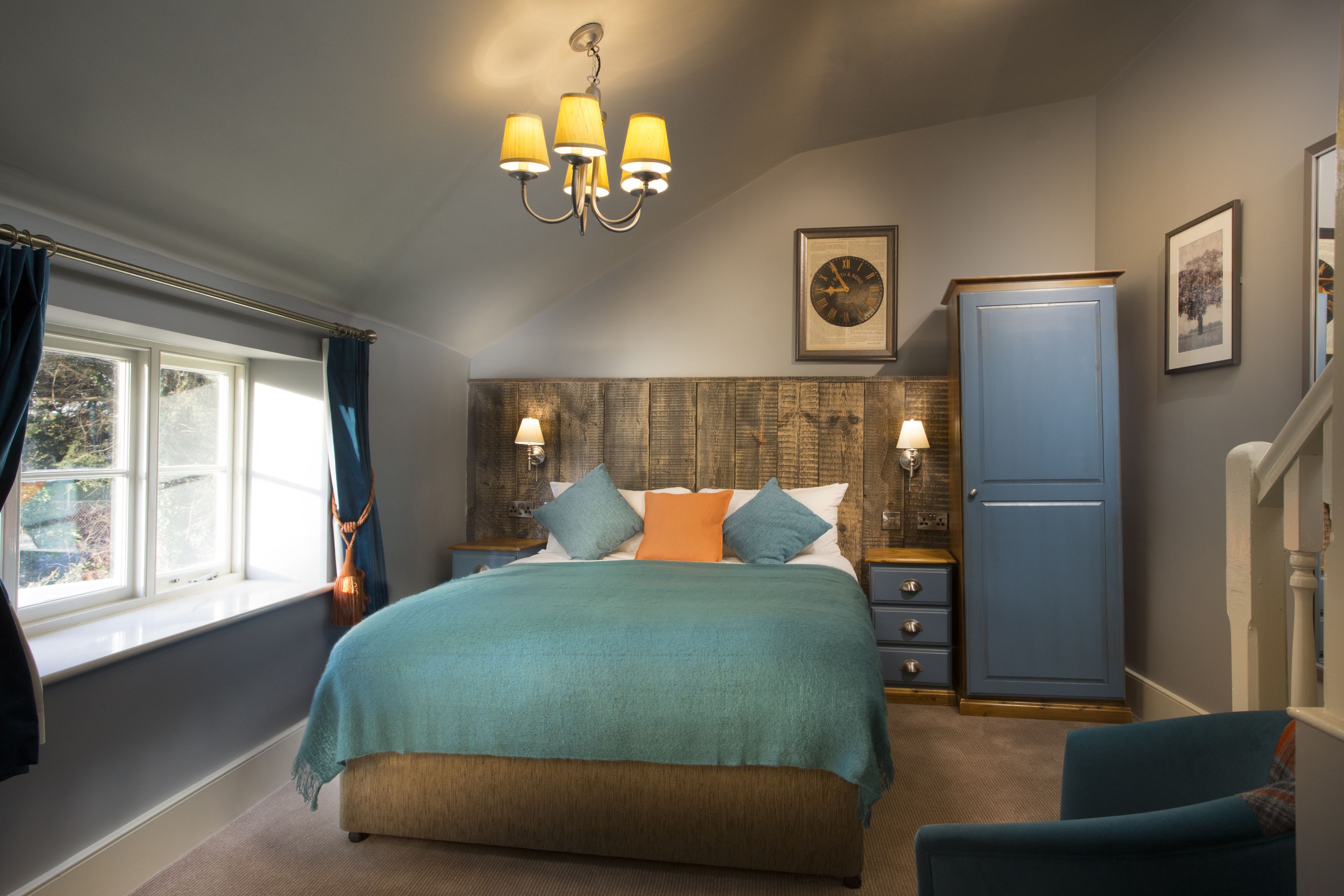 A bedroom with a bed, nightstands, a dresser, and a window with curtains.
