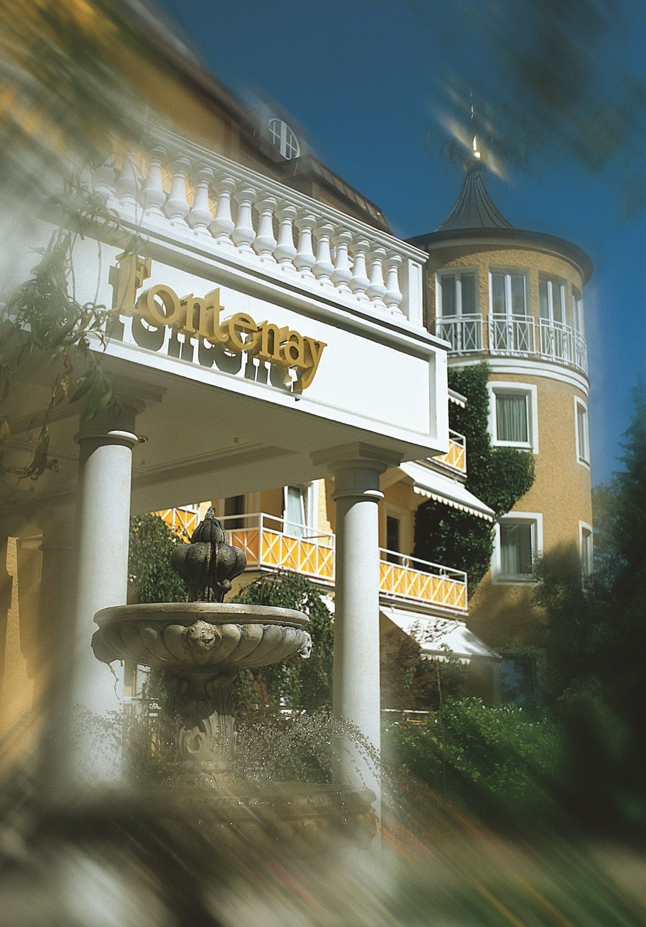 Ein Gebäude mit einem markanten „Fontemay“-Schild, einem Brunnen und einem Turm mit einem Balkon.