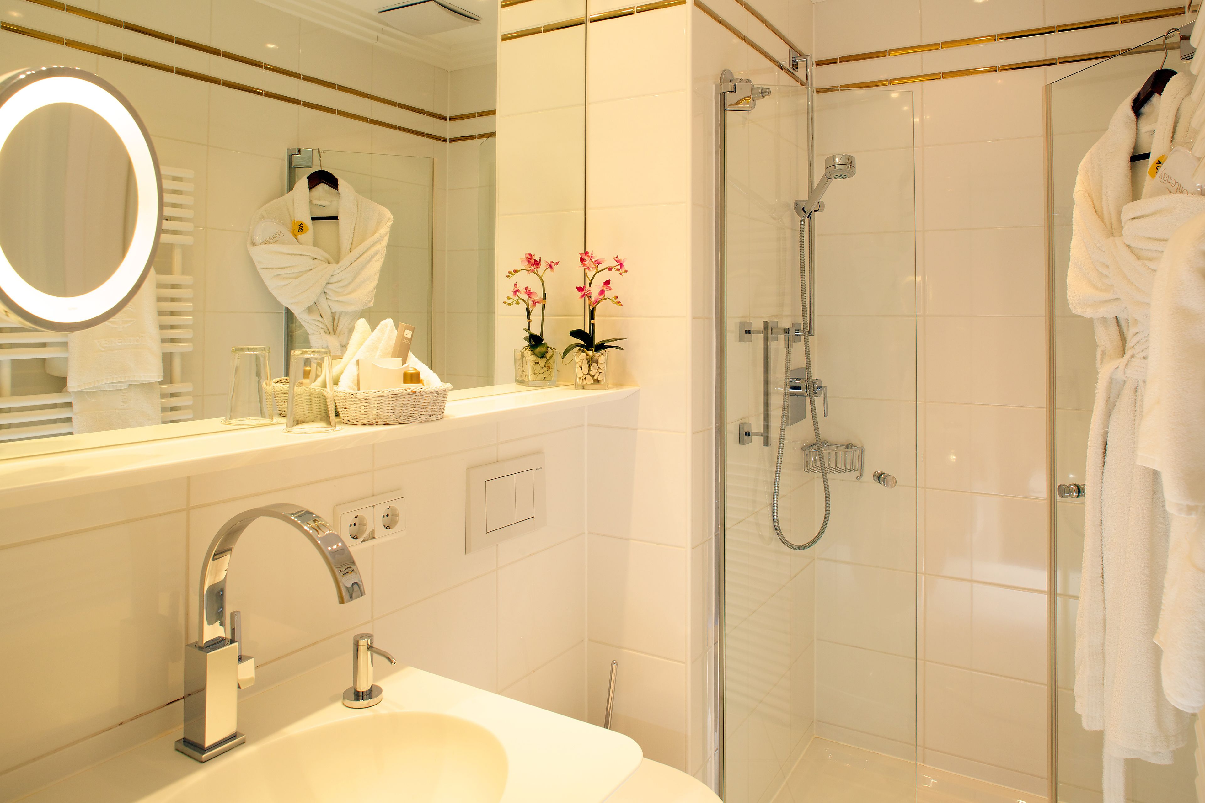 A modern bathroom with a sink, mirror, and shower.