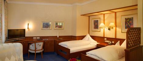 A hotel room with two beds, a desk, a TV, and a chair.