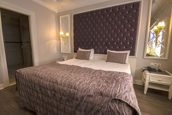 A bedroom with a large bed, a dark headboard, bedside lamps, and a nightstand.