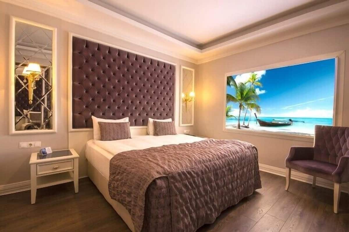 Un dormitorio con una cama grande, una ventana con vista al mar, una mesita de noche y una silla.