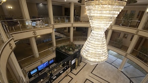 Vestíbulo de hotel de varios niveles con una gran araña espiral en el centro, varios pisos y un mostrador de recepción.
