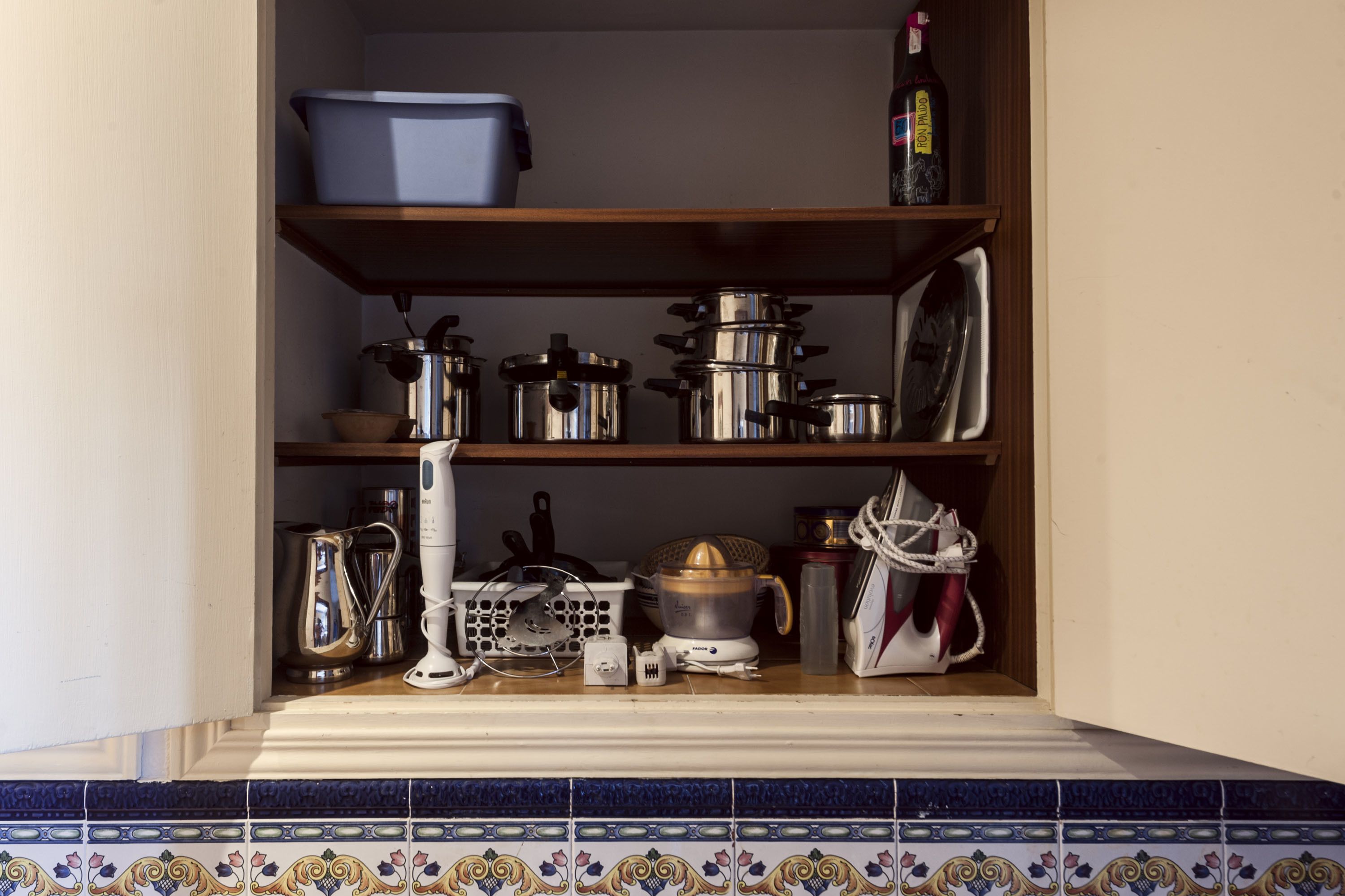 Una despensa de cocina con estantes que contienen ollas, sartenes, una cafetera y un hervidor.