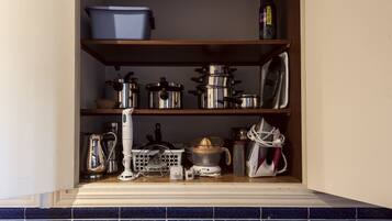 Una despensa de cocina con estantes que contienen ollas, sartenes, una cafetera y un hervidor.
