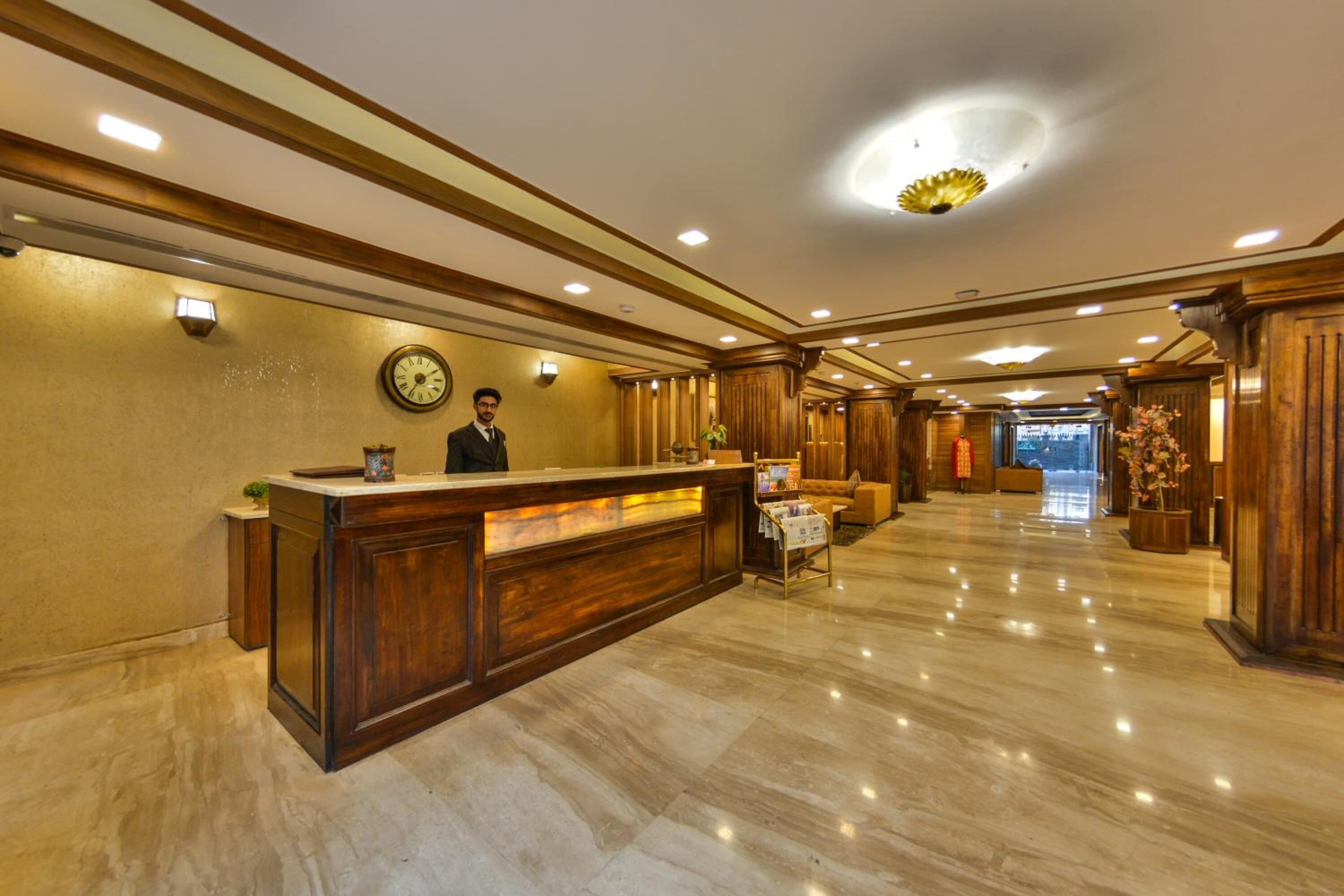 A hotel lobby with a reception desk, a clock, and a seating area.