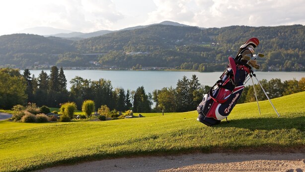 A golf bag on a tripod in a grassy area with a lake and mountains in the background. - Landhotel Kreinerhof - Self Check In 24h möglich (Lurnfeld)