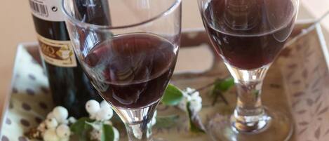 A plate of cured meat, a bottle of wine, and two glasses of red wine on a table with a polka dot tablecloth.