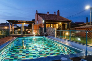 A swimming pool with a colorful tile pattern, surrounded by a wooden deck and a stone wall.