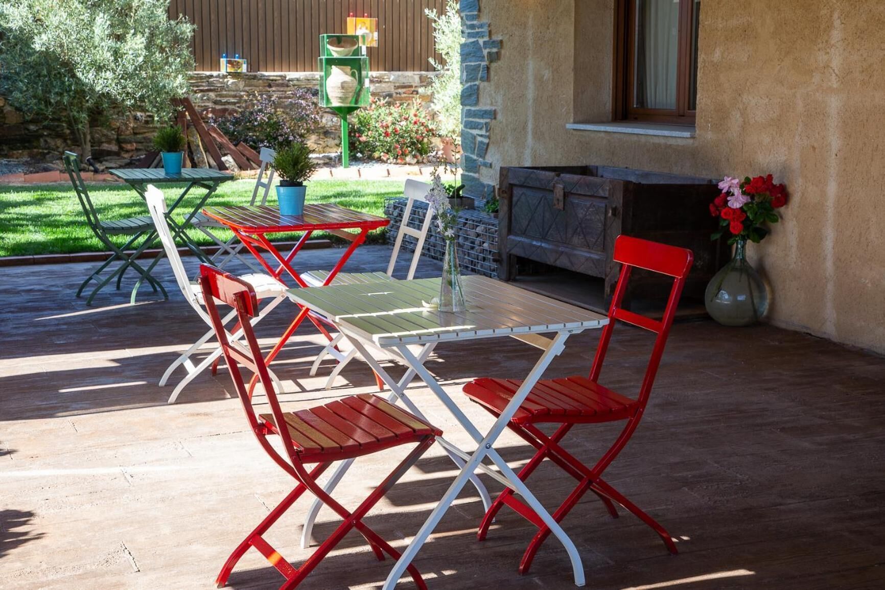 Una terrazza esterna con tavolo e sedie, un muro in pietra e una finestra.