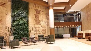 Eine moderne Lobby mit einer vertikalen Begrünung, bequemen Sitzgelegenheiten und einer großen Säule.