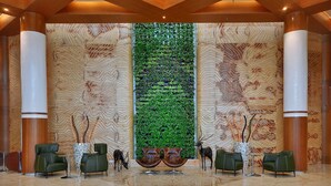 Eine Lobby mit einem großen, vertikalen Grünpflanzenwand, Holzwandverkleidung und Ledersesseln.