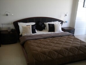 A bedroom with a large bed, a headboard, and two bedside tables.