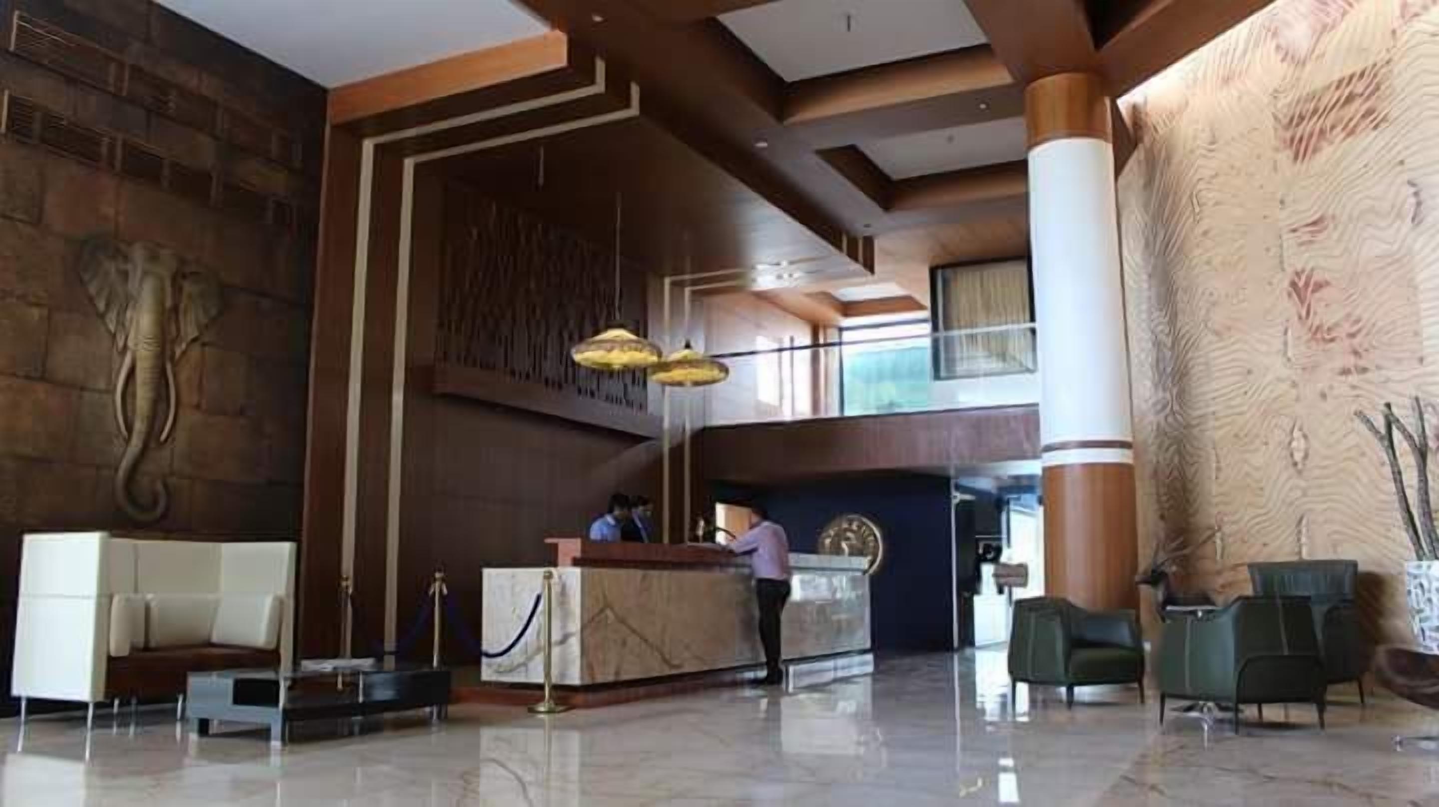 A spacious lobby with a reception desk, a large elephant sculpture, and a high ceiling with wooden beams.