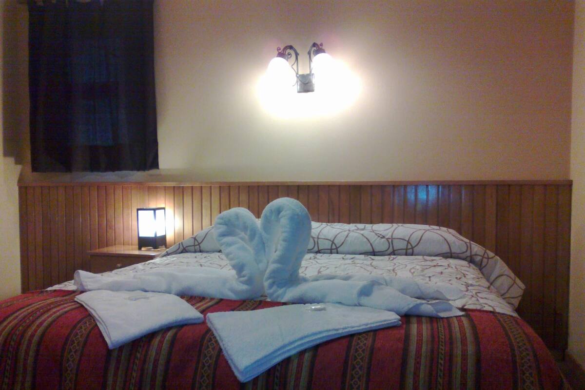 Una habitación de hotel con una cama, una mesita de noche y una lámpara fijada a la pared.