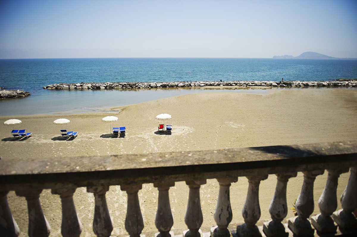 Una playa con una barandilla de piedra, una fila de sillas de playa y sombrillas.