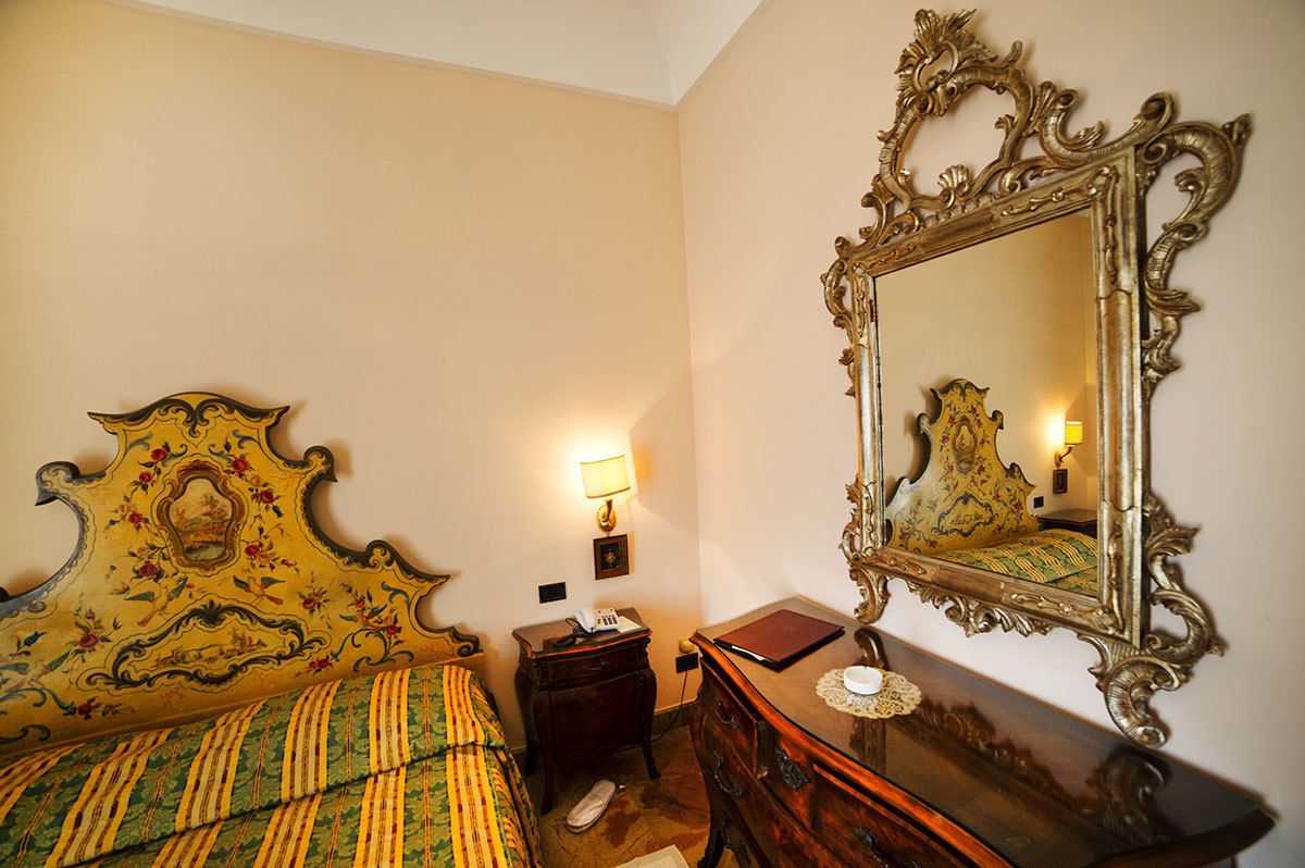 A room with a bed, a dresser, a mirror, and a nightstand with a lamp.