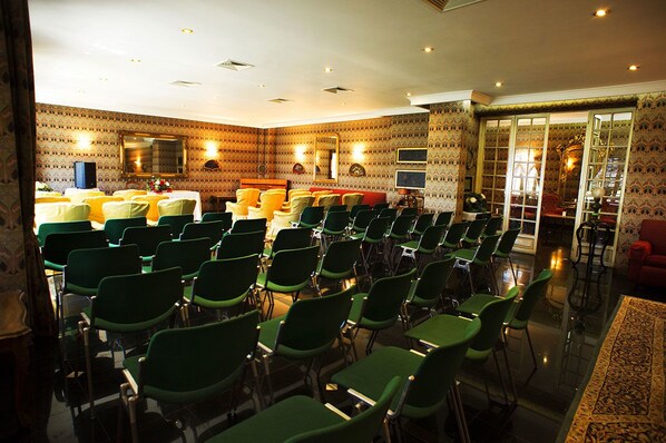 A conference room with rows of green chairs, a red sofa, and patterned wallpaper. - Grande Albergo Miramare (Formia)
