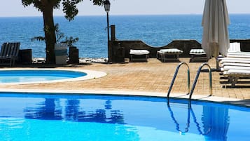 Una piscina al aire libre de temporada, sillones reclinables de piscina