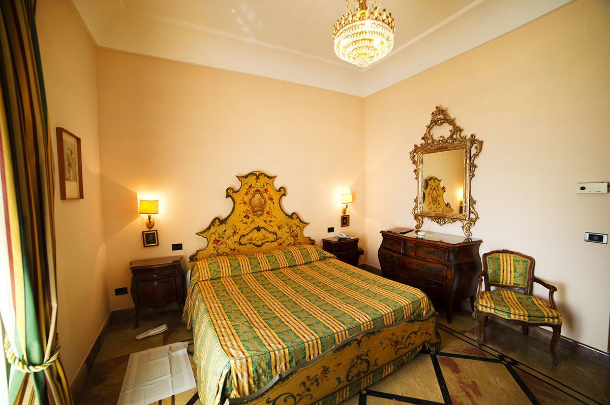 Une chambre d’hôtel avec un grand lit, deux tables de chevet, une commode, une chaise et un miroir.