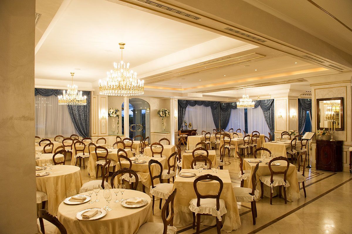 Un salón de banquetes con mesas redondas, sillas, candelabros y una elegante disposición para banquetear.