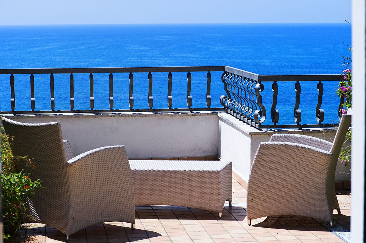 A balcony with wicker furniture and a view of the ocean.