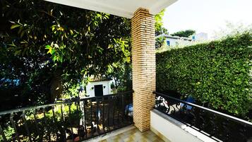 A balcony with a tiled floor, a brick pillar, and a black metal railing.