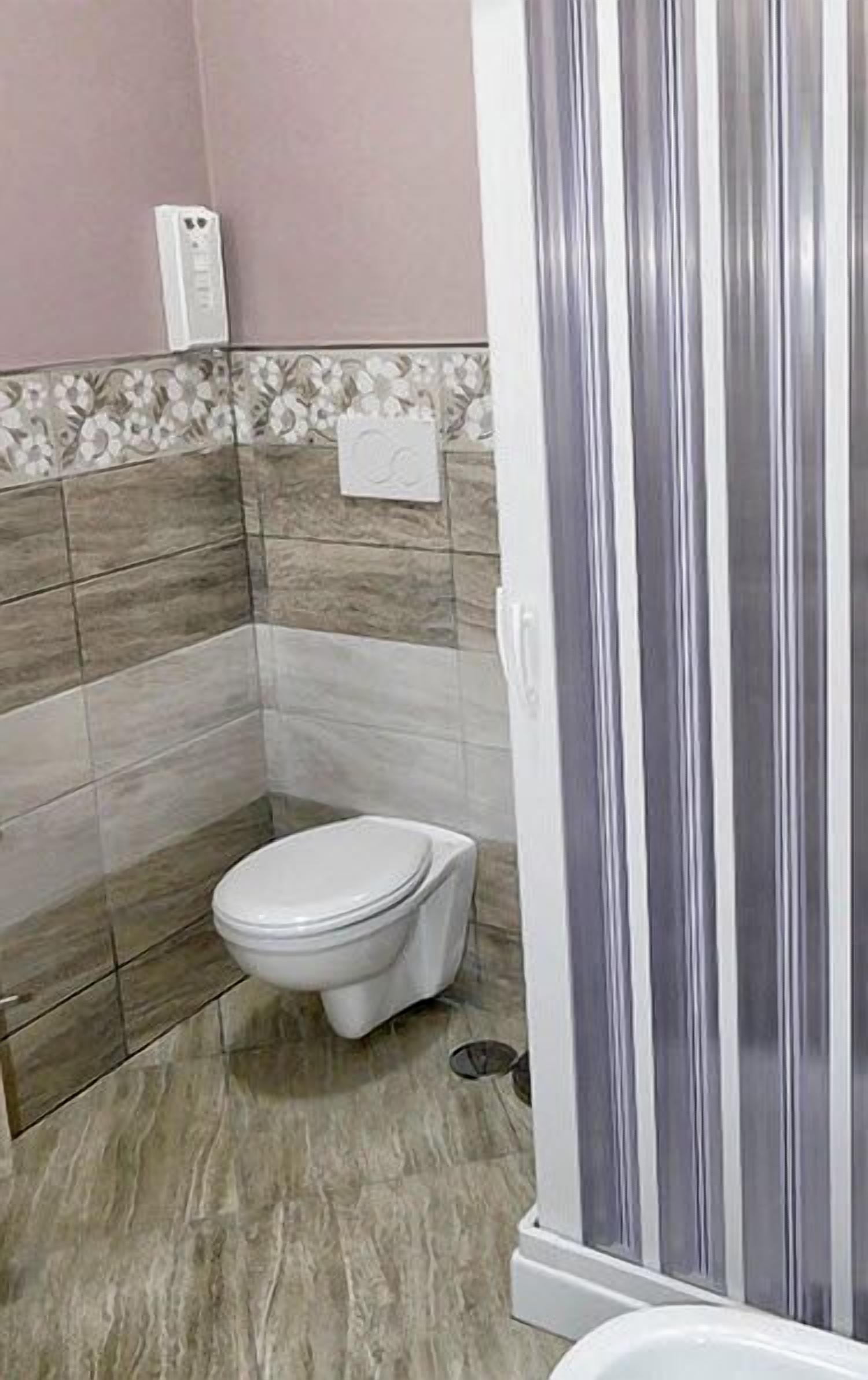 A bathroom with a toilet, a shower with a glass door, and tiled walls.