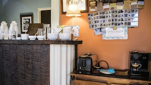 Un coin café équipé d’un grille-pain, d’une machine à café et de différents types de tasses et de mugs.