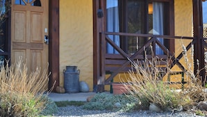 Un bâtiment rustique avec une porte en bois, une fenêtre ornée de rideaux et une balustrade en bois.