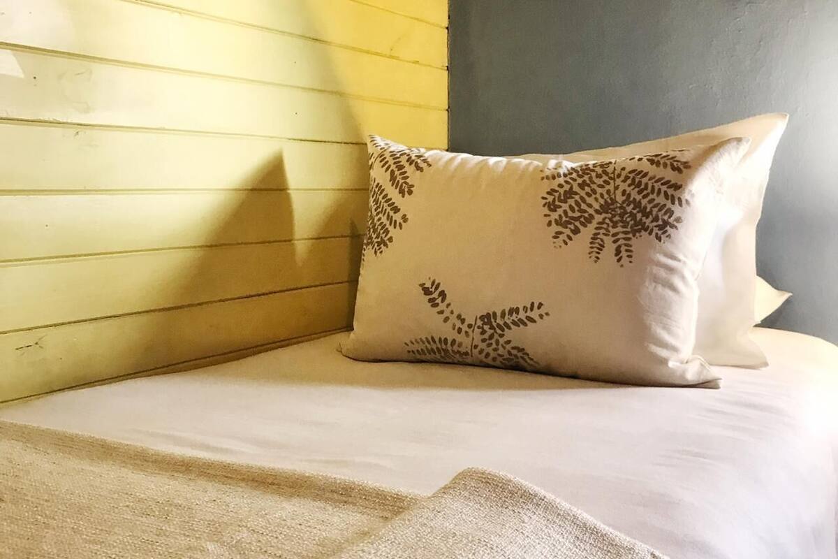 Cama bem arrumada com manta dobrada e travesseiro decorativo.