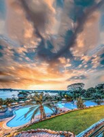 Un resort con piscina, zonas de descanso y vista al agua.