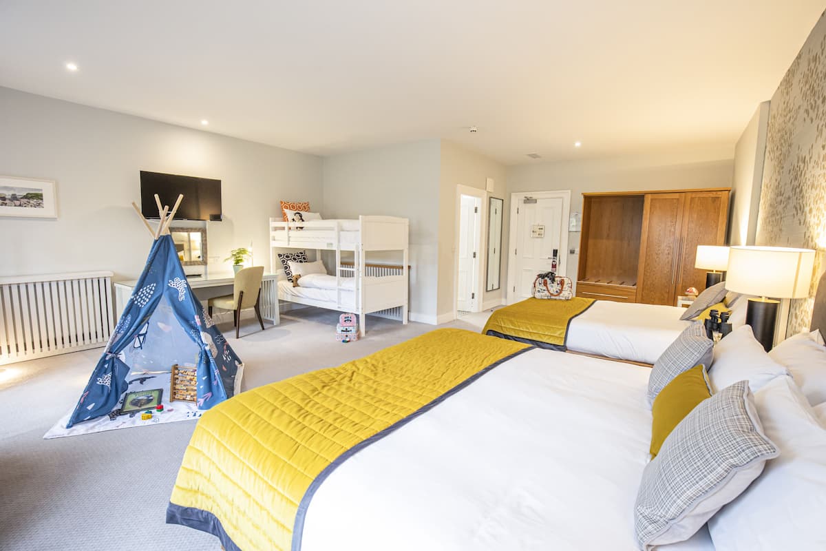 Une chambre d’hôtel avec des lits superposés, une tente, un bureau et une lampe.