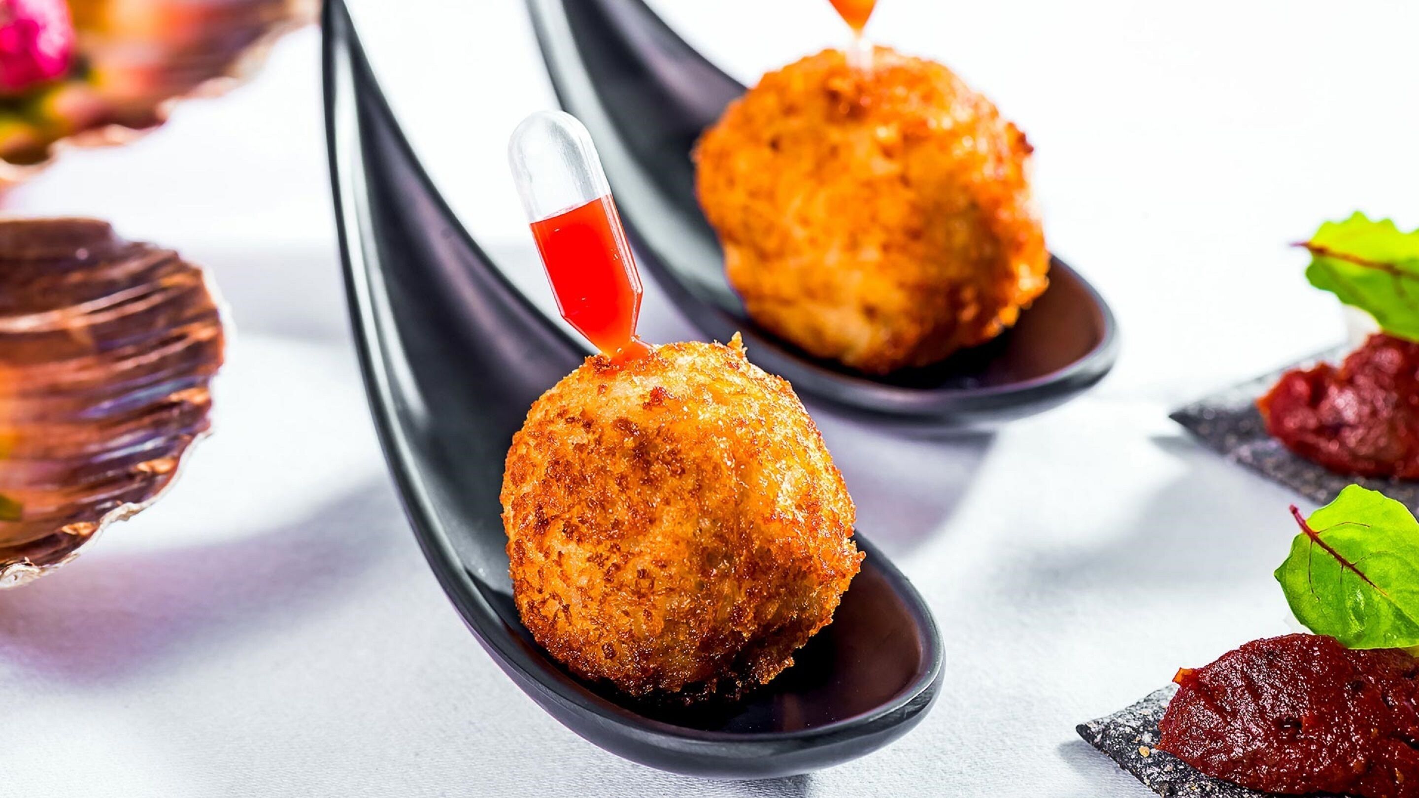 Una cuchara con un alimento y salsa roja.
