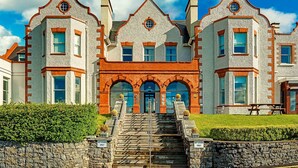 A large, historic building with a symmetrical facade, multiple windows, and a central entrance with a set of stairs leading up to it. - Mulranny Park Hotel (Mulranny)