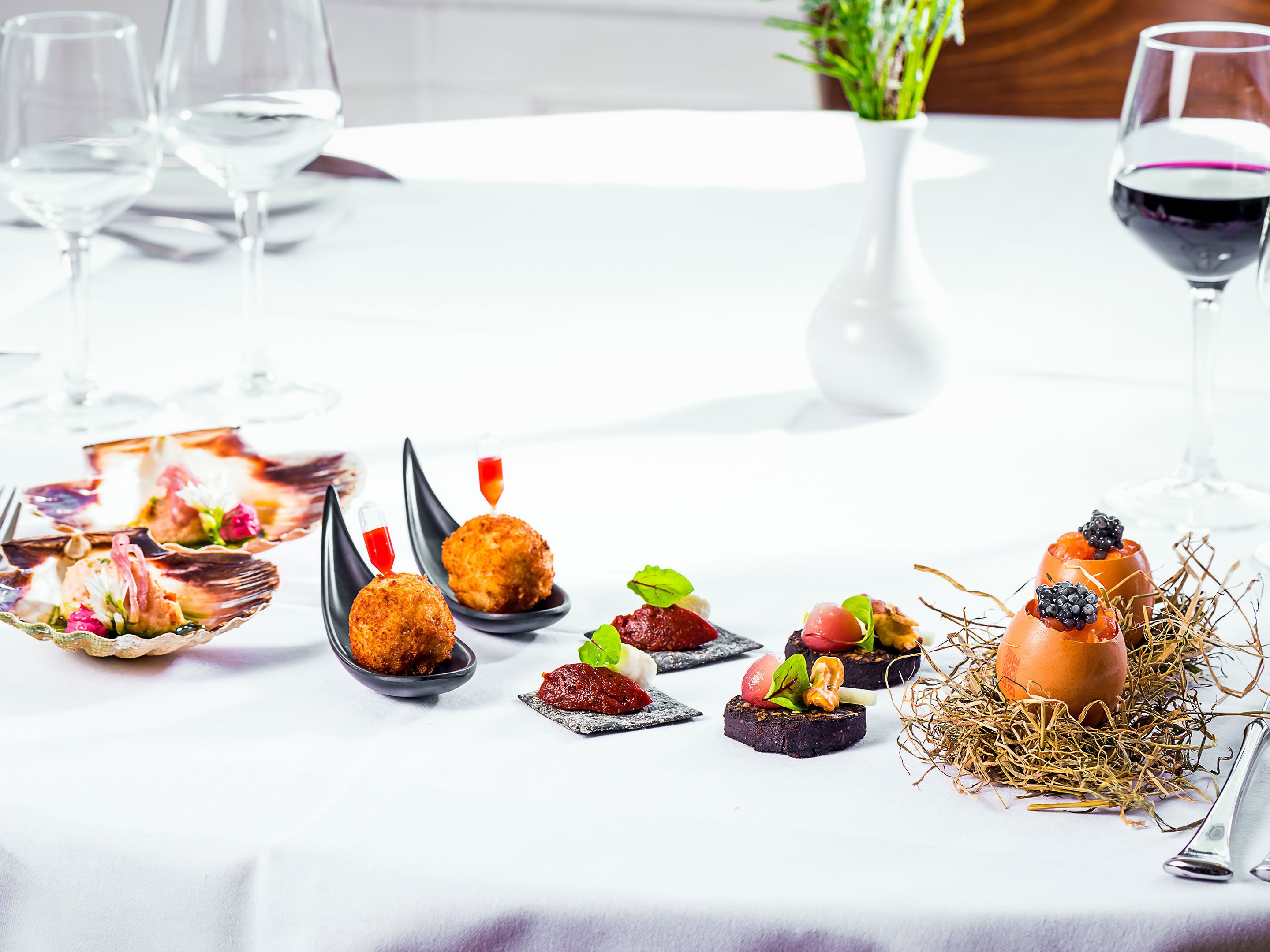 A table set with various appetizers and a glass of red wine.