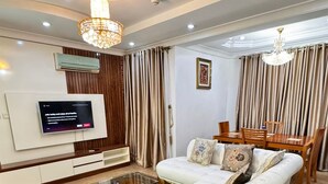 Una sala de estar moderna con un sofá blanco, una mesa de centro de cristal y una zona de comedor con mesa y sillas de madera.