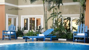 Un área de piscina con sillas reclinables azules y un letrero que dice "Casa Valletta Suites & Apartments".