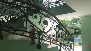Una escalera de caracol con barandillas de metal ornamentadas y vistas a zonas verdes al aire libre.