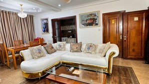 Una sala de estar con un sofá seccional blanco, una mesa de centro de vidrio y una araña.