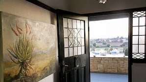 Een kamer met uitzicht op een landelijk landschap door een raam met decoratief traliewerk.