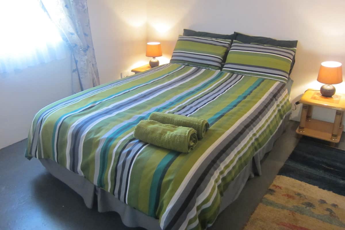 A bed with striped bedding, two bedside lamps, and a small table with a lamp.