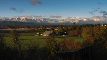 A rural landscape with a barn, open fields, and distant mountains.