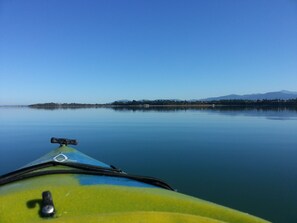 A kayak on calm water with a clear view of a distant shoreline and mountains. - GreenHouse Inn by the Bay (Sequim)