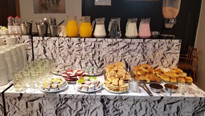 A buffet with various food items and beverages, including juices, milk, and pastries. - Hotel Monte Cervino (San Carlos de Bariloche)