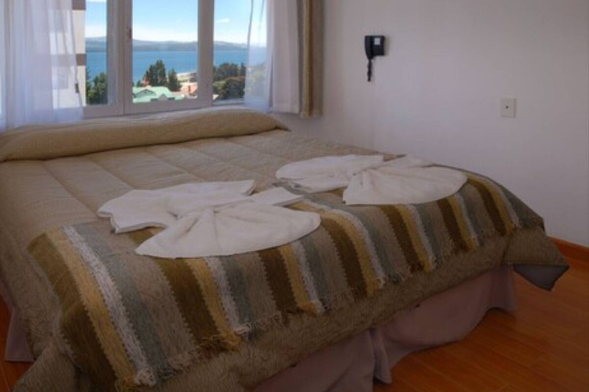 Un letto con una coperta a righe e due asciugamani bianchi piegati sopra.