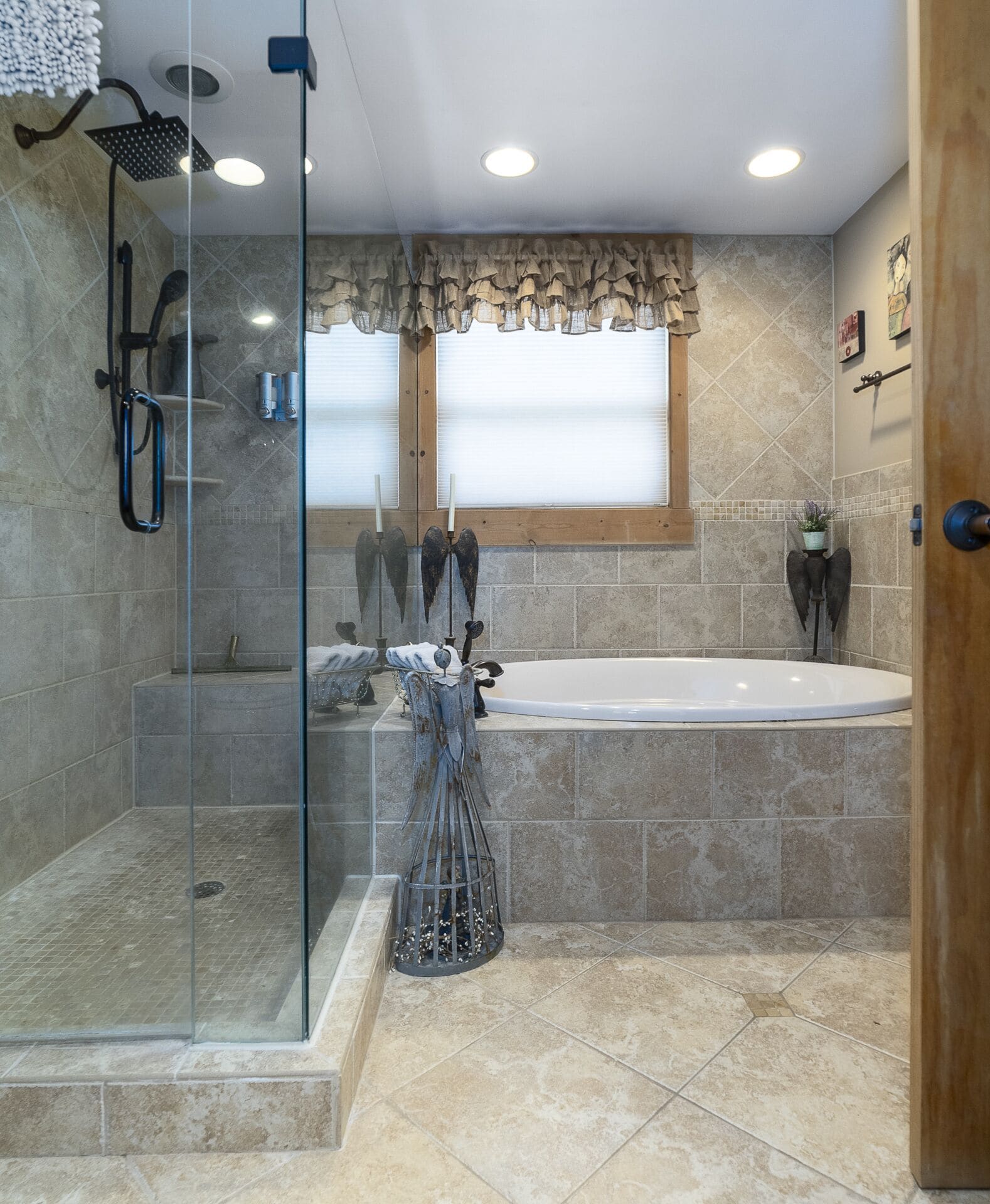 A modern bathroom with a glass-enclosed shower, a freestanding bathtub, and a decorative angel statue.