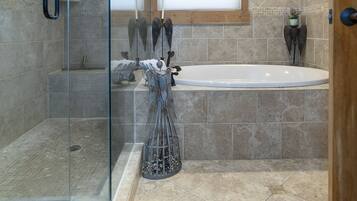 A modern bathroom with a glass-enclosed shower, a freestanding bathtub, and a decorative angel statue.