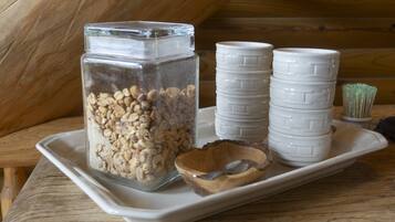 A tray with a glass jar of oats, a wooden bowl, and stacked white ceramic cups.