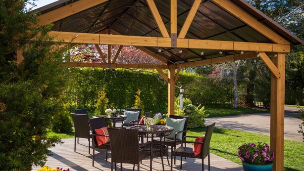 Une terrasse couverte, aménagée avec du mobilier d’extérieur et des plantes en pot.
